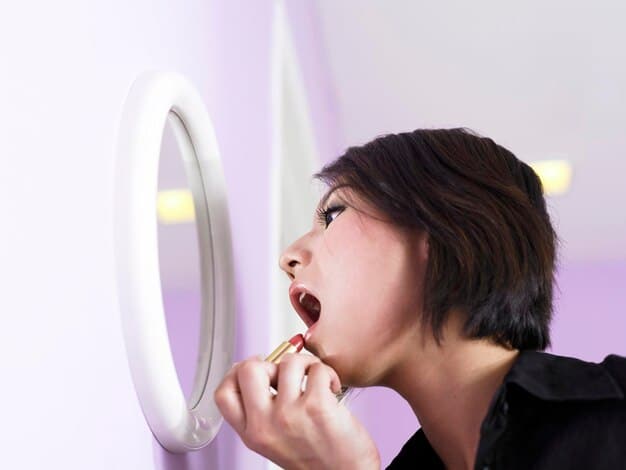 A close-up photo of a K-Pop idol during vocal warm-up, with focus on their throat and mouth muscles. The artist is performing a lip trill exercise, with a determined and focused expression.