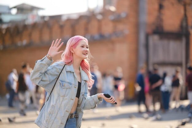 A behind-the-scenes candid shot of a K-Pop idol laughing with their group members during a music video shoot for their latest release, displaying them in unguarded and candid moment. The setting is vibrant and energetic, with crew members and equipment subtly visible in the background.